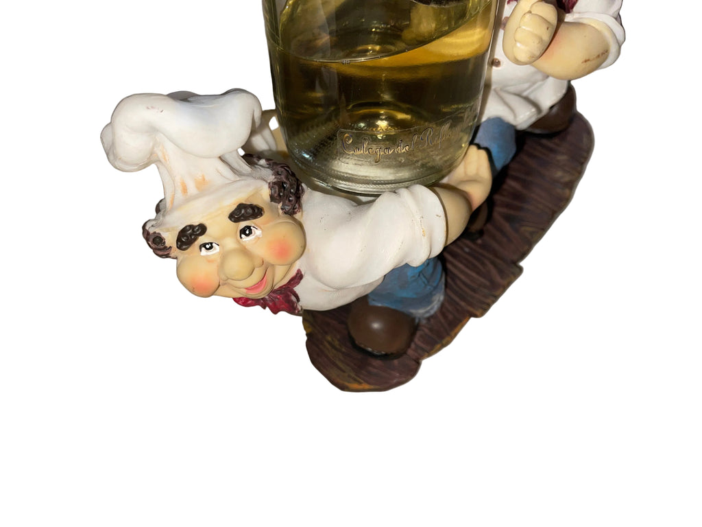 Decorative figurine of a chef holding a glass of wine on a striped surface