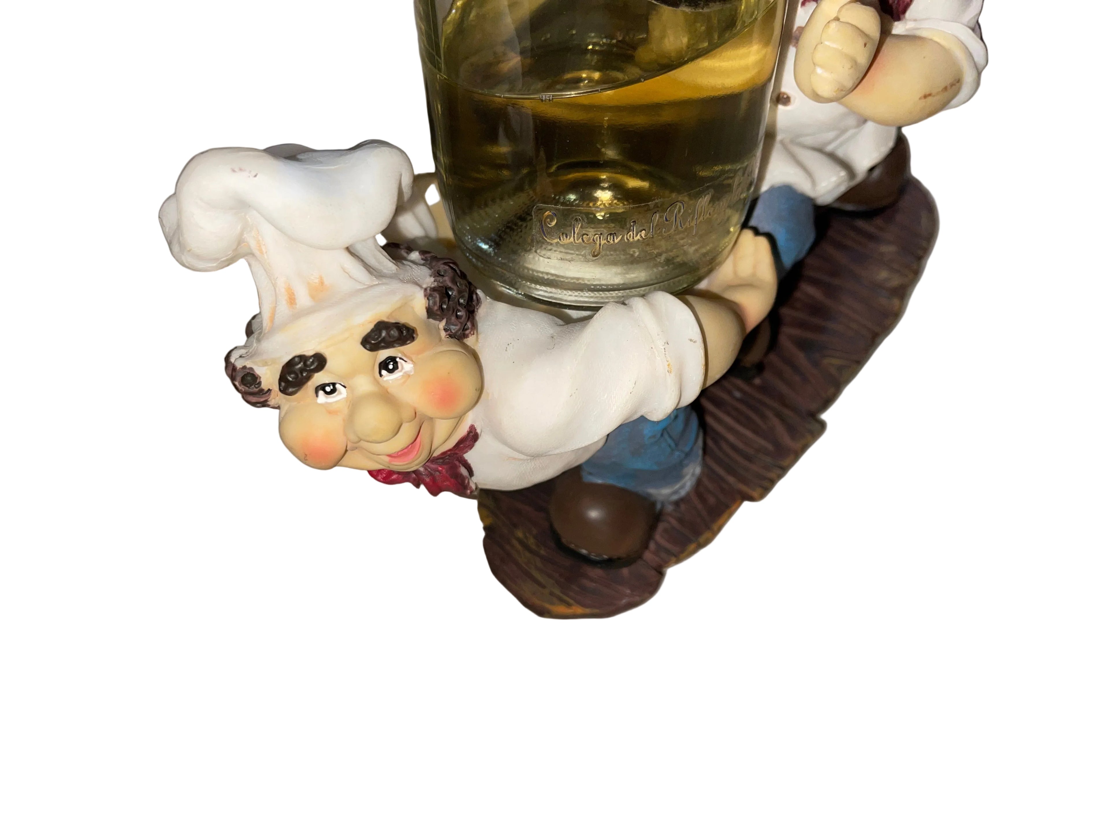 Decorative figurine of a chef holding a glass of wine on a striped surface